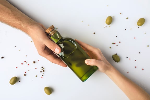 cropped-image-of-man-and-woman-holding-olive-oil-